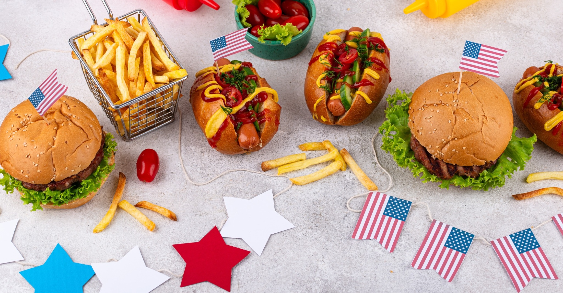 250 Years of Feeding America Fourth of July spread with burgers, hot dogs, fries, condiments, and American flags celebrating foodservice in America.